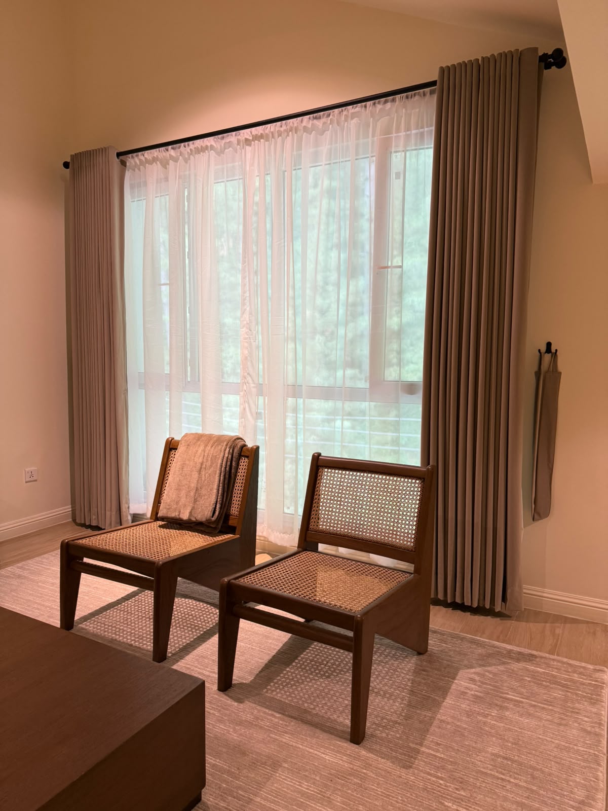 Rattan lounge chairs by the forest-facing window in a completed apartment at MYG Nathiagali